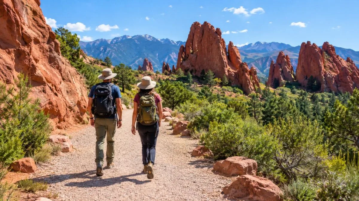 Two hikers seen from behind on a wide trail among red rock formations